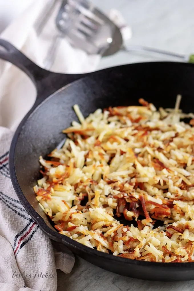 The photo shows crispy hash browns cooked in a cast iron skillet.