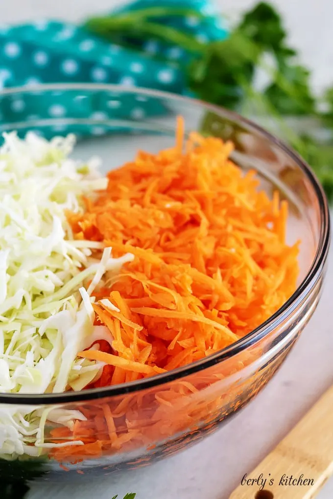 A large mixing bowl filled with shredded cabbage and carrots.