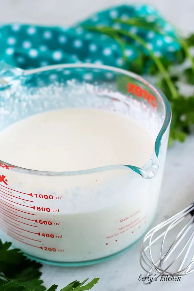 The coleslaw dressing has been mixed in a large measuring cup.