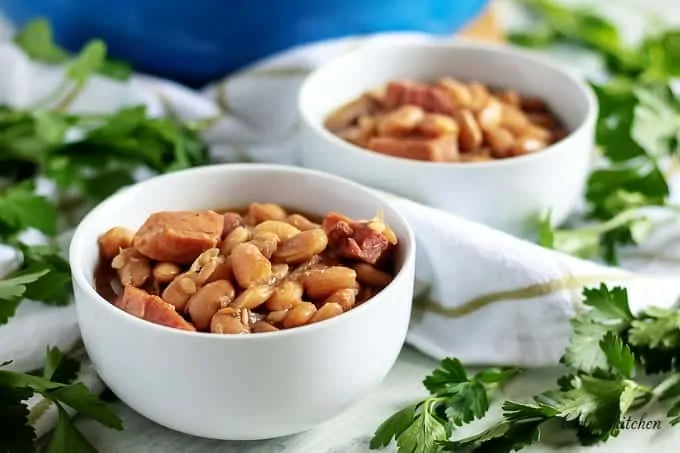 Two bowls of ham and beans garnished with fresh parsley.