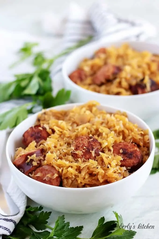 The finished kielbasa and sauerkraut served in two bowls with parsley.