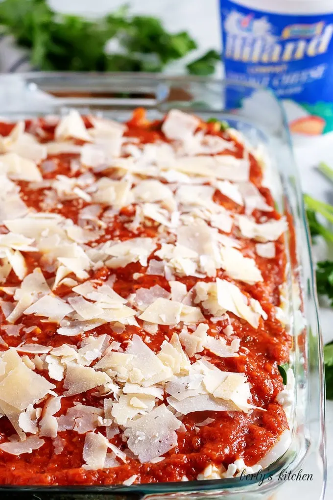 The final layer of marinara and shaved parmesan cheese, just before baking.