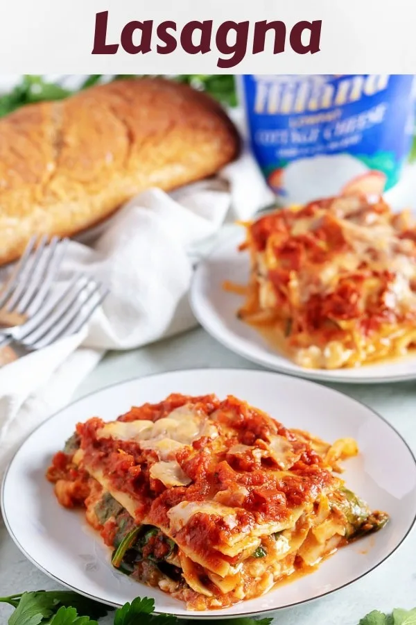 Two slices of mushroom lasagna, served with a loaf of wheat bread.