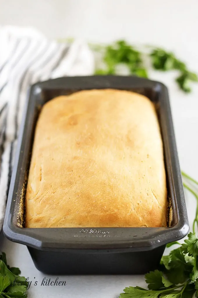 The bread has baked and risen in the loaf pan.