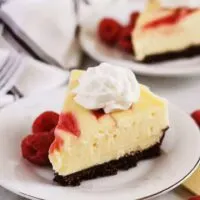 Slices of instant pot white chocolate raspberry cheesecake topped with whipped cream.