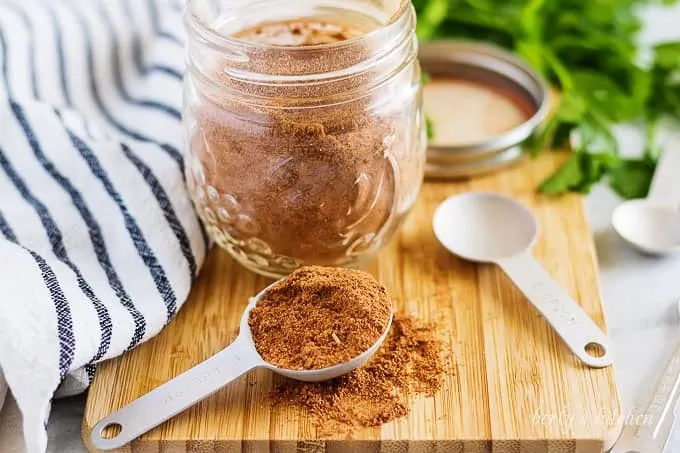 A mason jar filled with taco seasoning sitting on a cutting board.