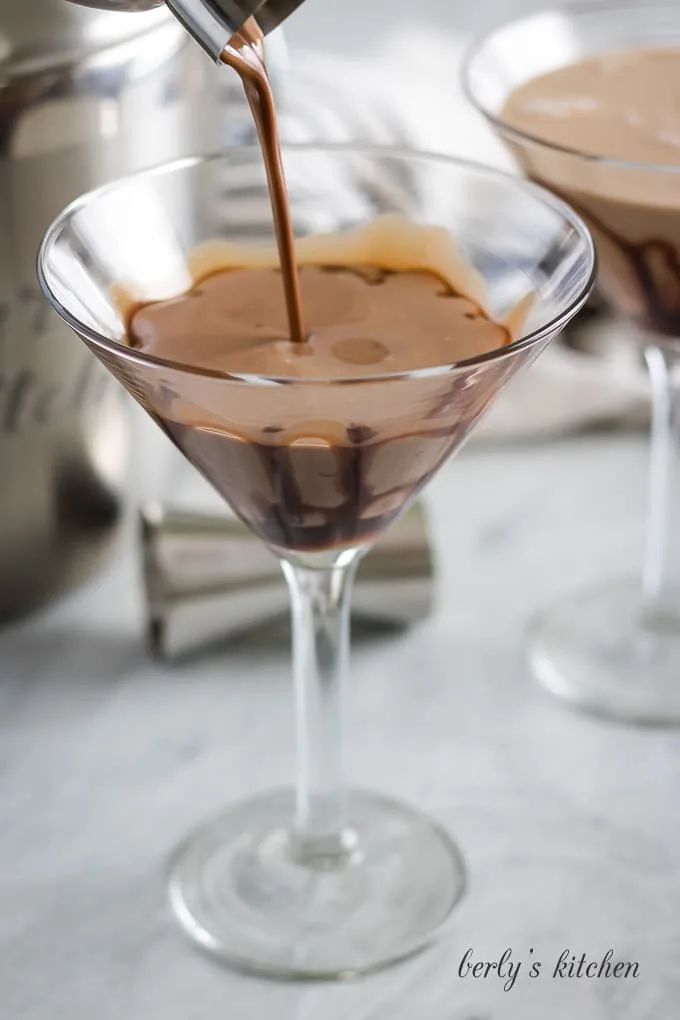 The espresso and hazelnut mixed drink being poured into the glass.