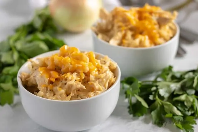 Two bowls of ranch style chicken and rice topped with shredded cheddar.