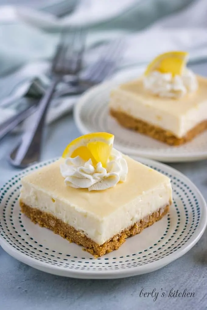 The lemon cheesecake bars garnished with whipped cream, and lemon wedges.