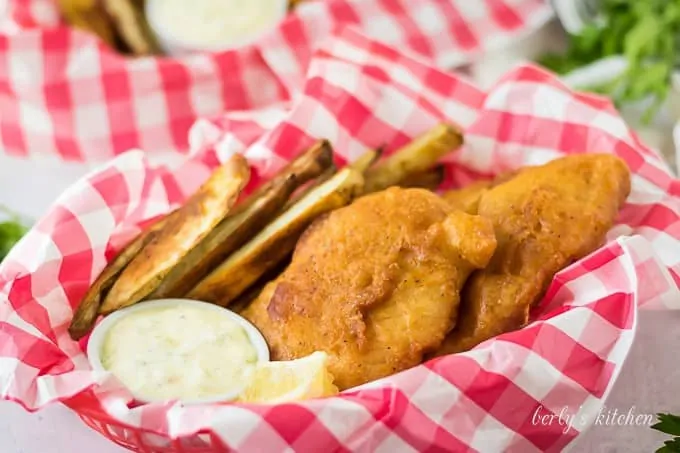 A filet of beer battered cod served with fries and tartar sauce.