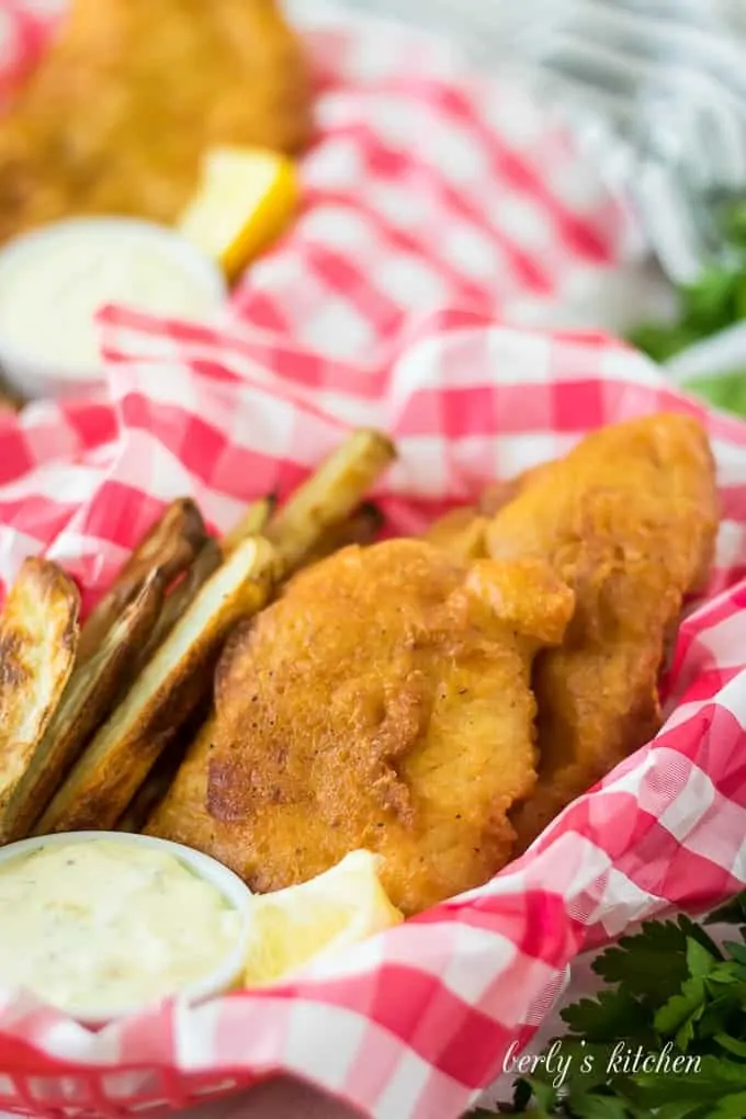 Fried fish, in a basket, served with fries and tartar sauce.