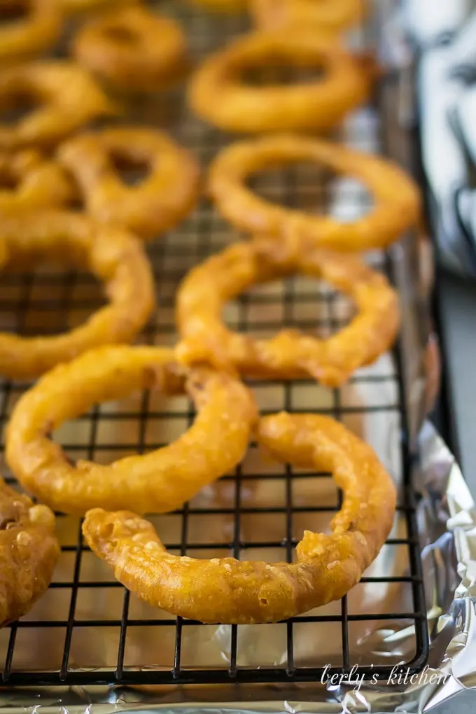 A prepared wire rack with foil holding the fried onion rings.