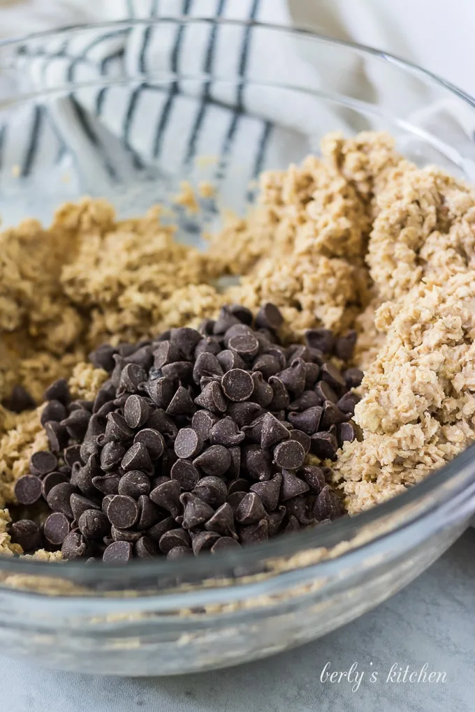 A cup of chocolate chips have been poured into the bowl.