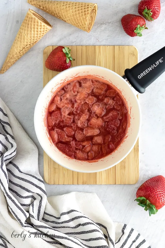 Berries, sugar, and lemon juice simmered in a pan for a sauce.