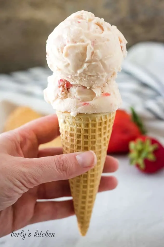 Two large scoops of strawberry ice cream in a waffle cone.