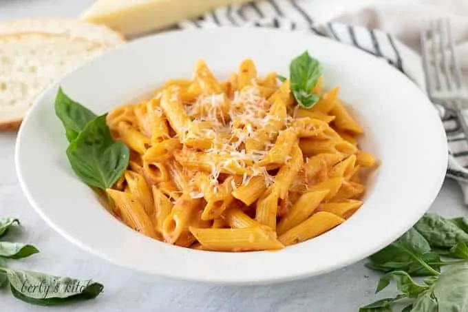 A white bowl filled with the tomato pasta garnished with fresh basil.