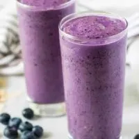 Two large glasses of the blueberry smoothie surrounded by berries.