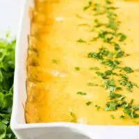 The baked cheesy enchiladas garnished with fresh chopped parsley.