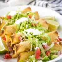 The baked chicken taquitos topped with lettuce, tomatoes, and guacamole.