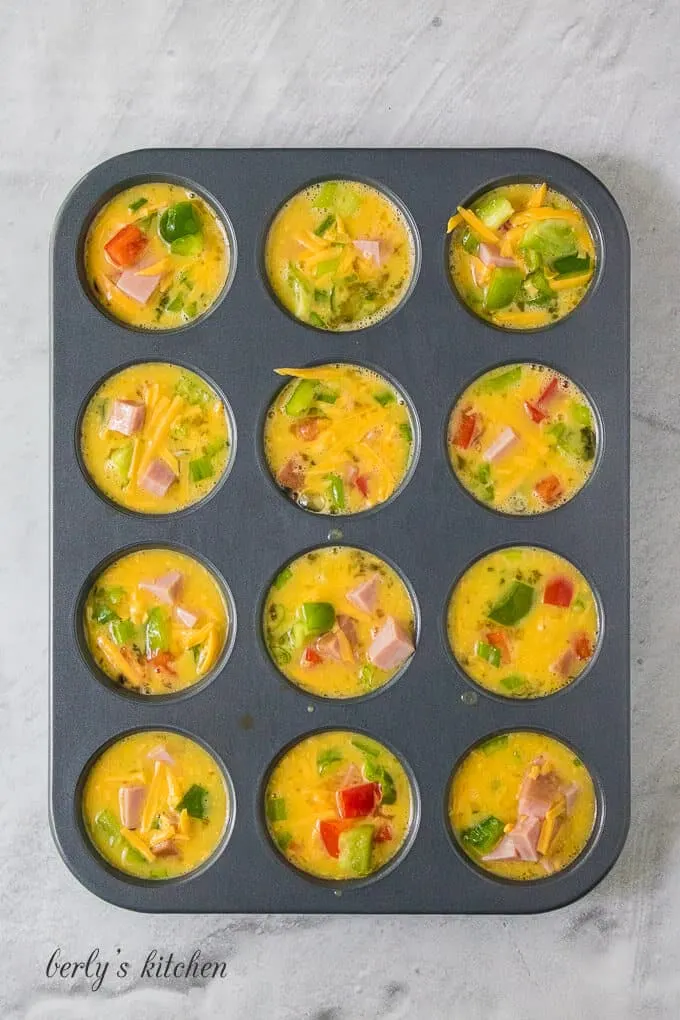 The denver omelette ingredients have been transferred to a muffin tin.