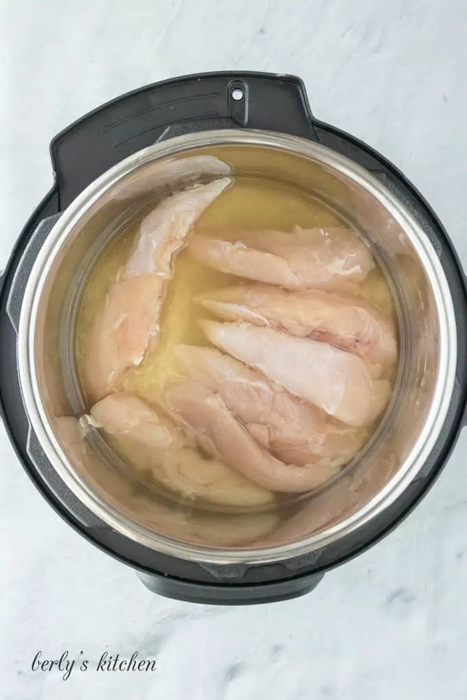 The broth, meat, and rice in the pressure cooker liner.