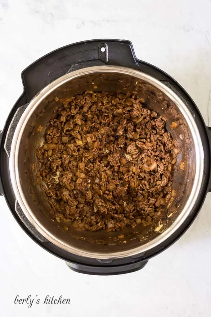 Ground beef, onions, and other ingredients sauteed in the cooker.