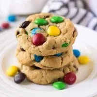 A stack of cookies on a white plate with candy.