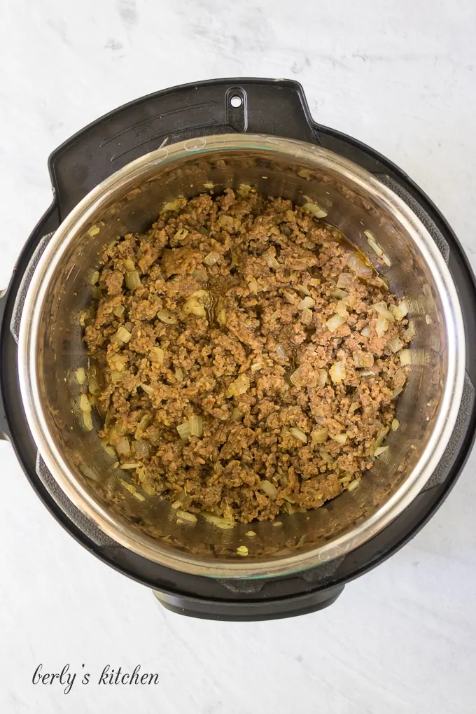 Meat, vegetables, and spices being cooked in the pressure cooker.