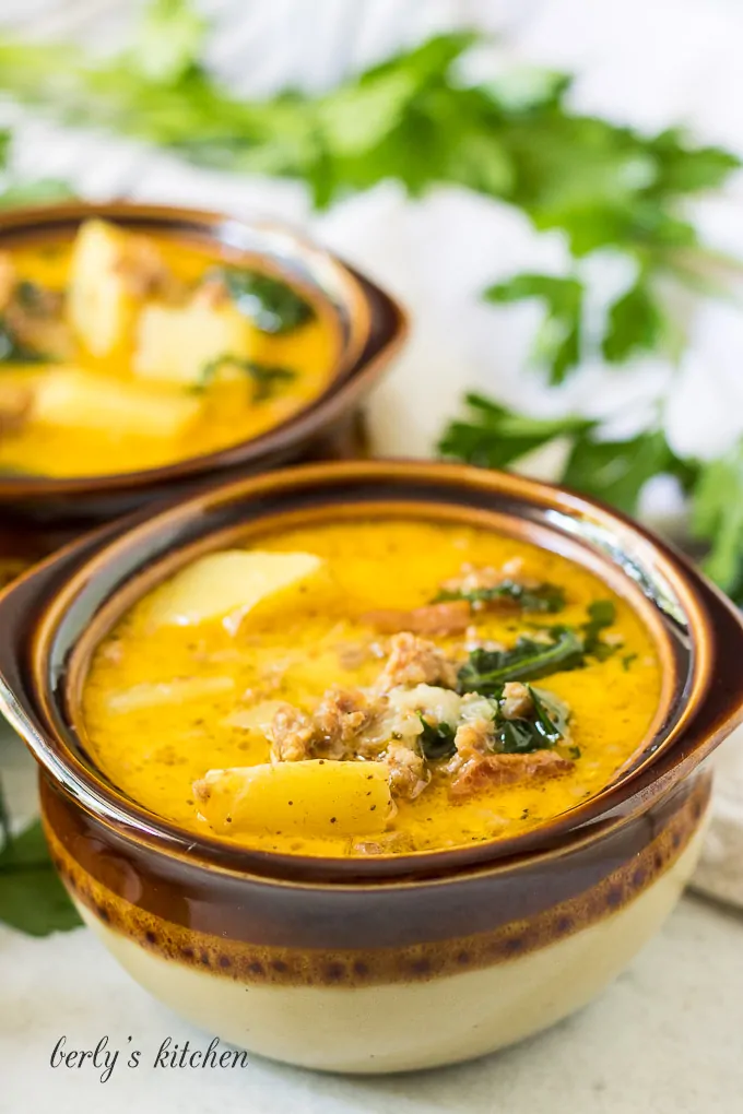 Two brown decorative bowls filled with zuppa toscana soup.