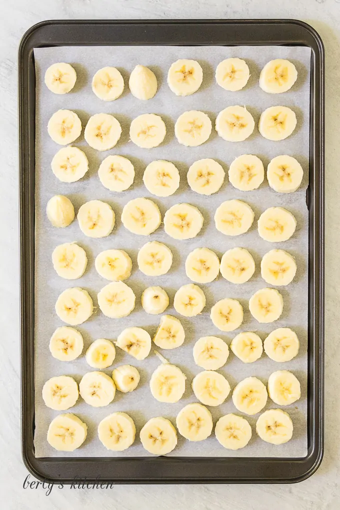 Bananas have been sliced and placed on a sheet pan.