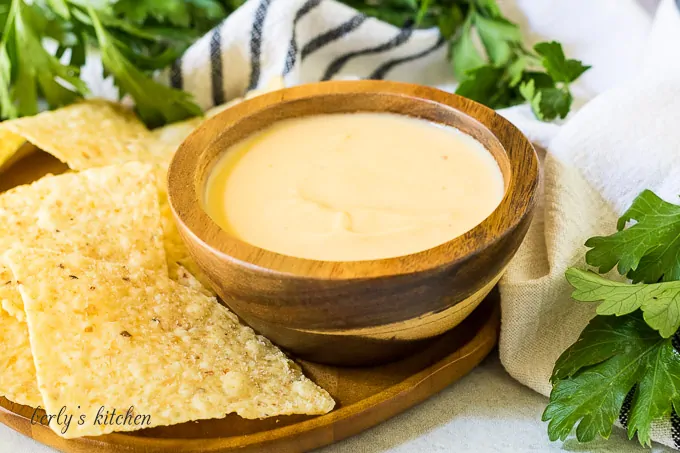 A small wooden bowl of beer cheese dip with chips.