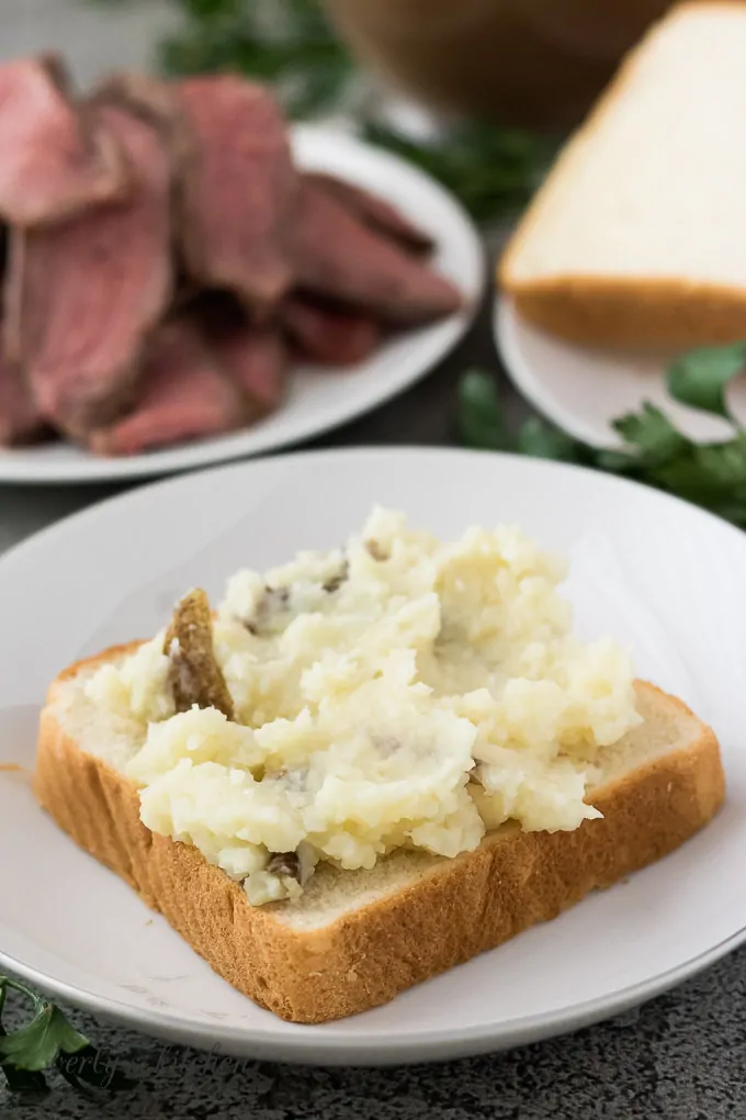 Texas toast topped with mashed potatoes on a white plate.