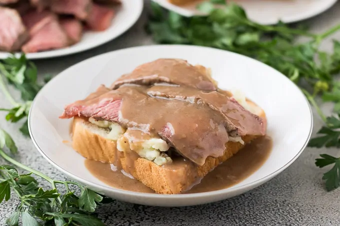 Leftover pot roast atop mashed potatoes and bread topped with gravy.