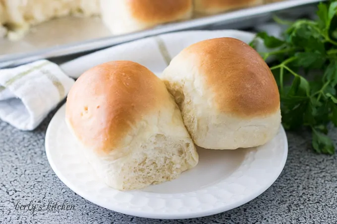 Two yeast rolls topped with butter on a decorative saucer.