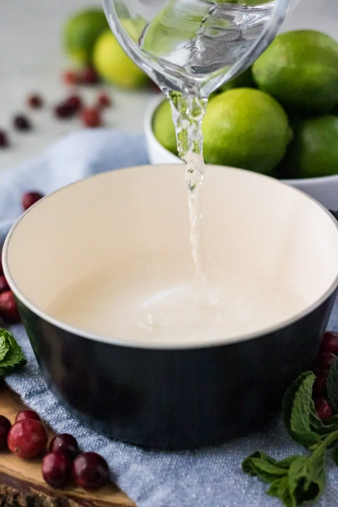 Water being poured into a saucepan with sugar in it.