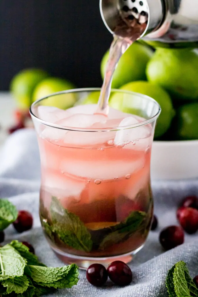 The mock cranberry cocktail being poured into a glass with ice.