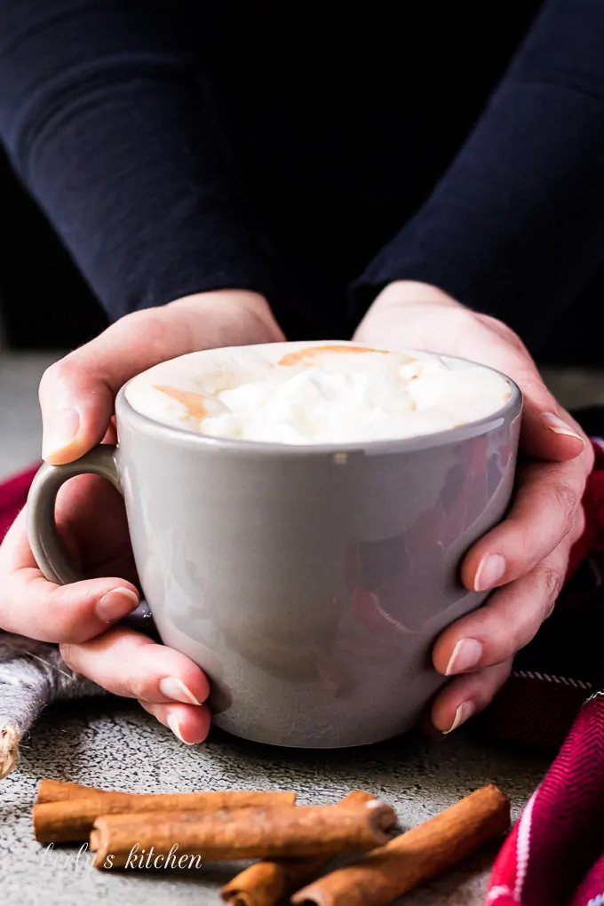 Hand model holding a mug of the gingerbread hot chocolate.