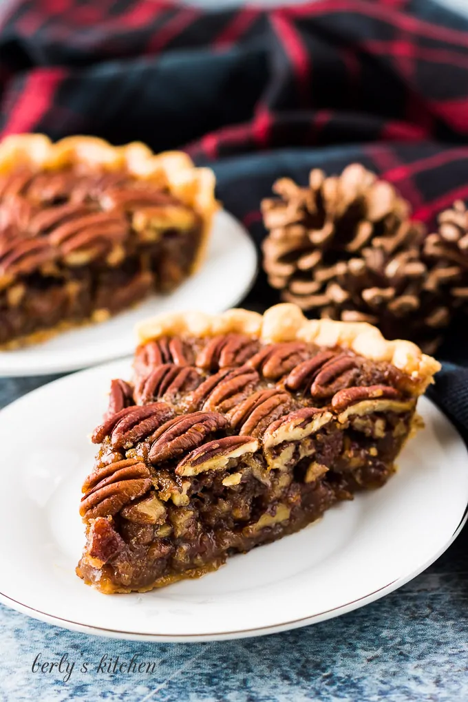 Two slices of pecan pie served on small decorative saucers.