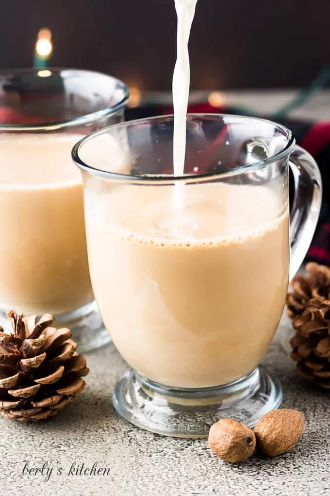 Milk being added to the mug with coffee and eggnog.