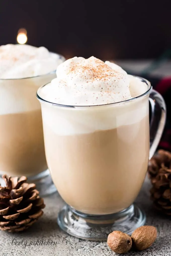 Two finished eggnog latte coffee drinks served with whipped cream.