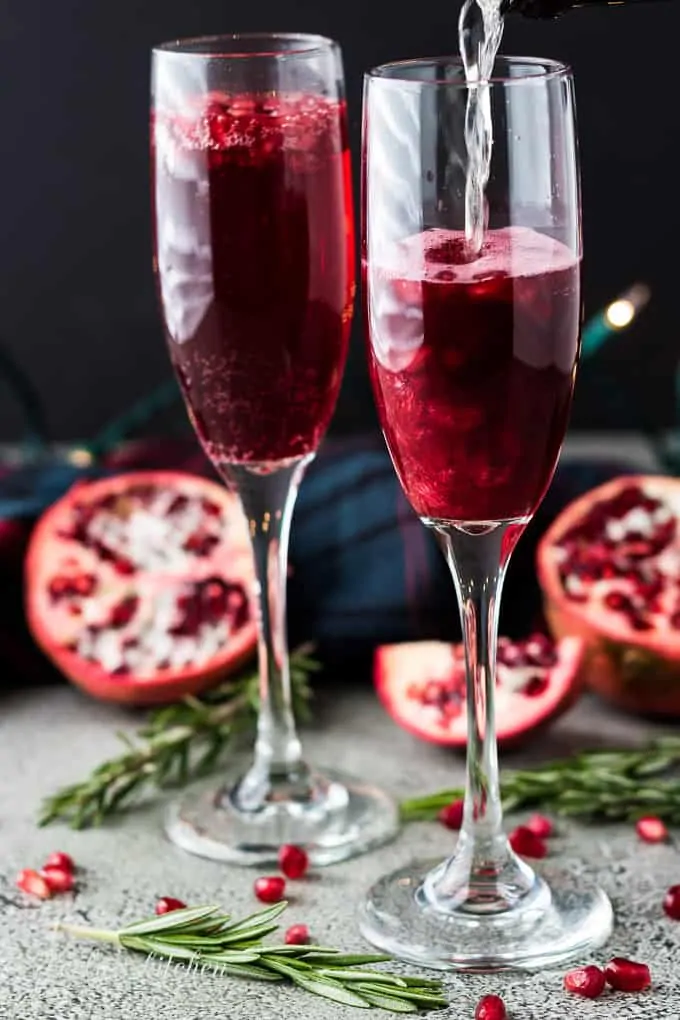 Champagne being poured into the glasses filled with fruit juice.