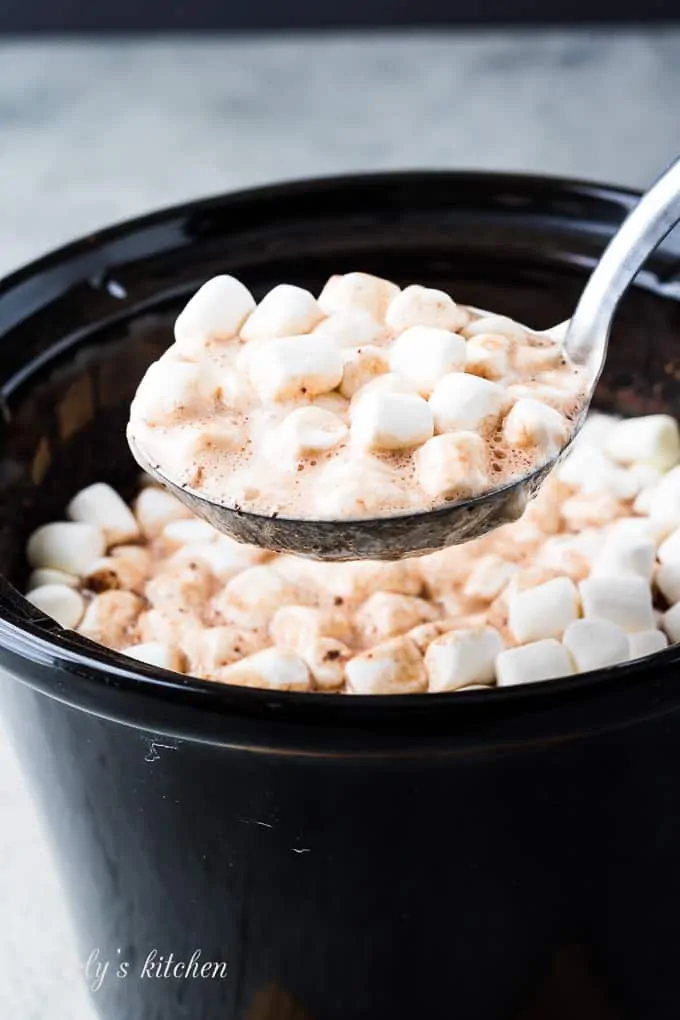 A large ladle of the cocoa topped with melting marshmallows.