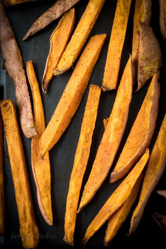 Close up of baked sweet potato fries on a sheet pan.