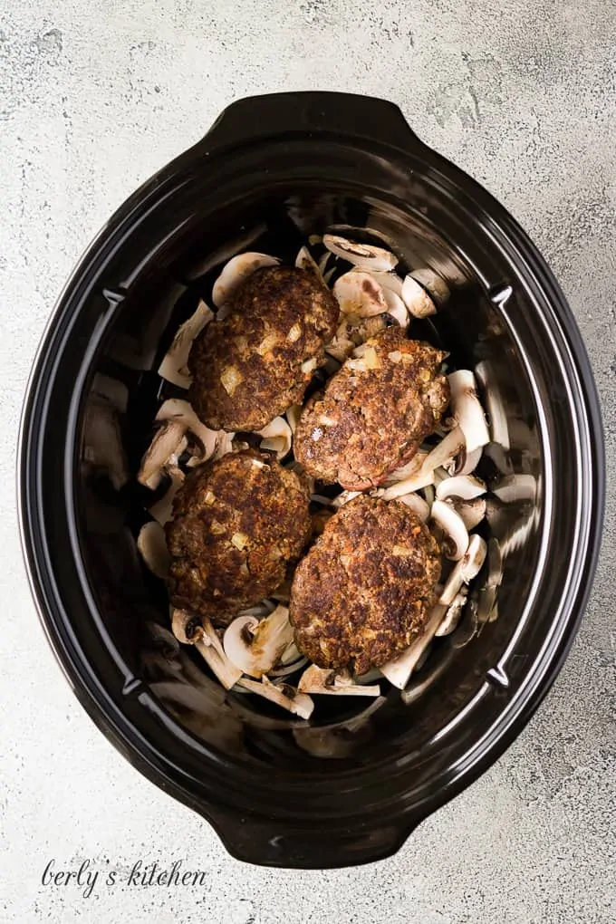 The beef placed on top of the mushrooms in the crockpot.