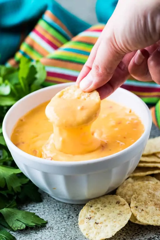 Berly dipping a round tortilla chip into the cheese dip.