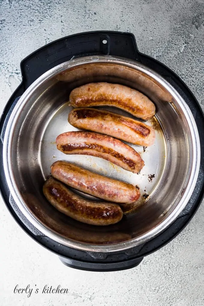 Five italian sausage links sauteing in the preheated pressure cooker.