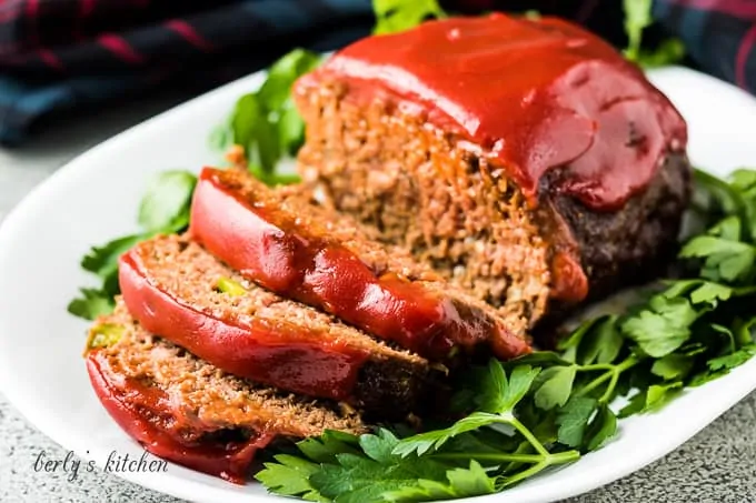 The sliced meatloaf on a platter and topped with ketchup.