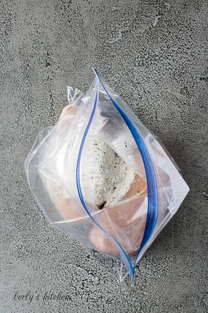 Two chicken breasts in a freezer bag with ranch seasoning.