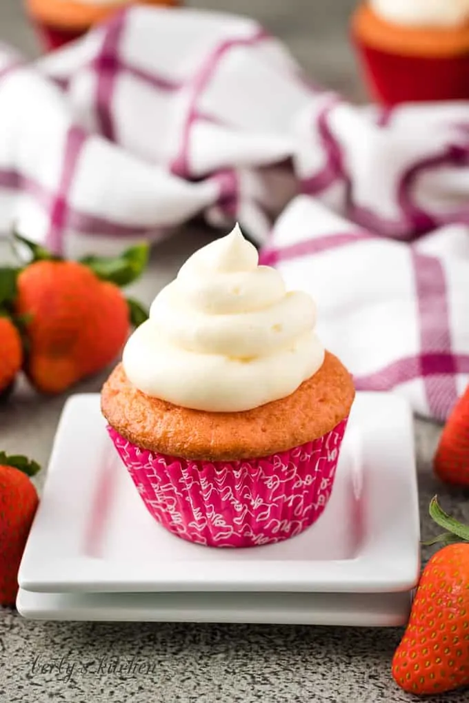 A single cupcake on a decorative plate topped with frosting.