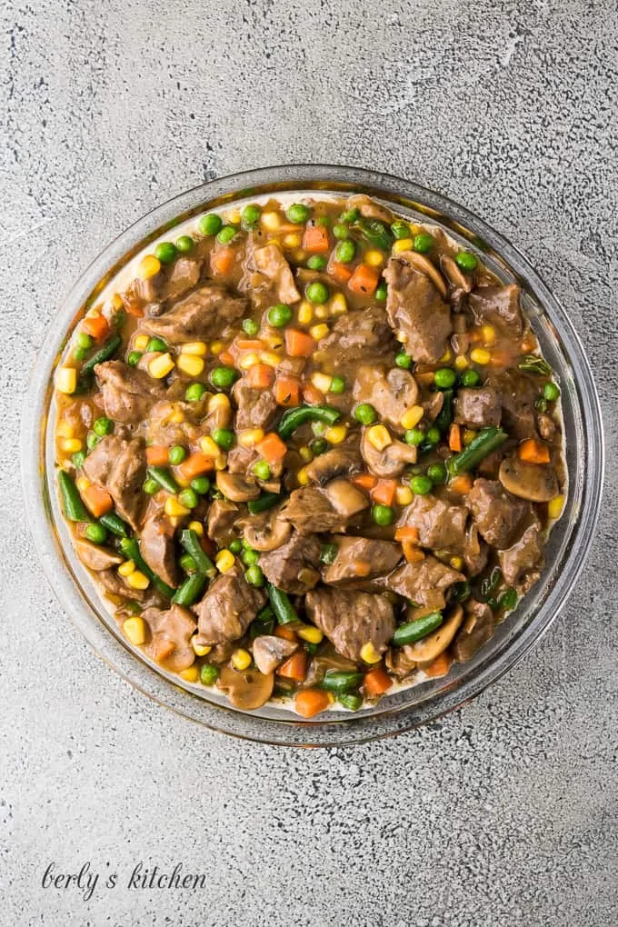 The beef pot pie filling transferred to a pie pan.